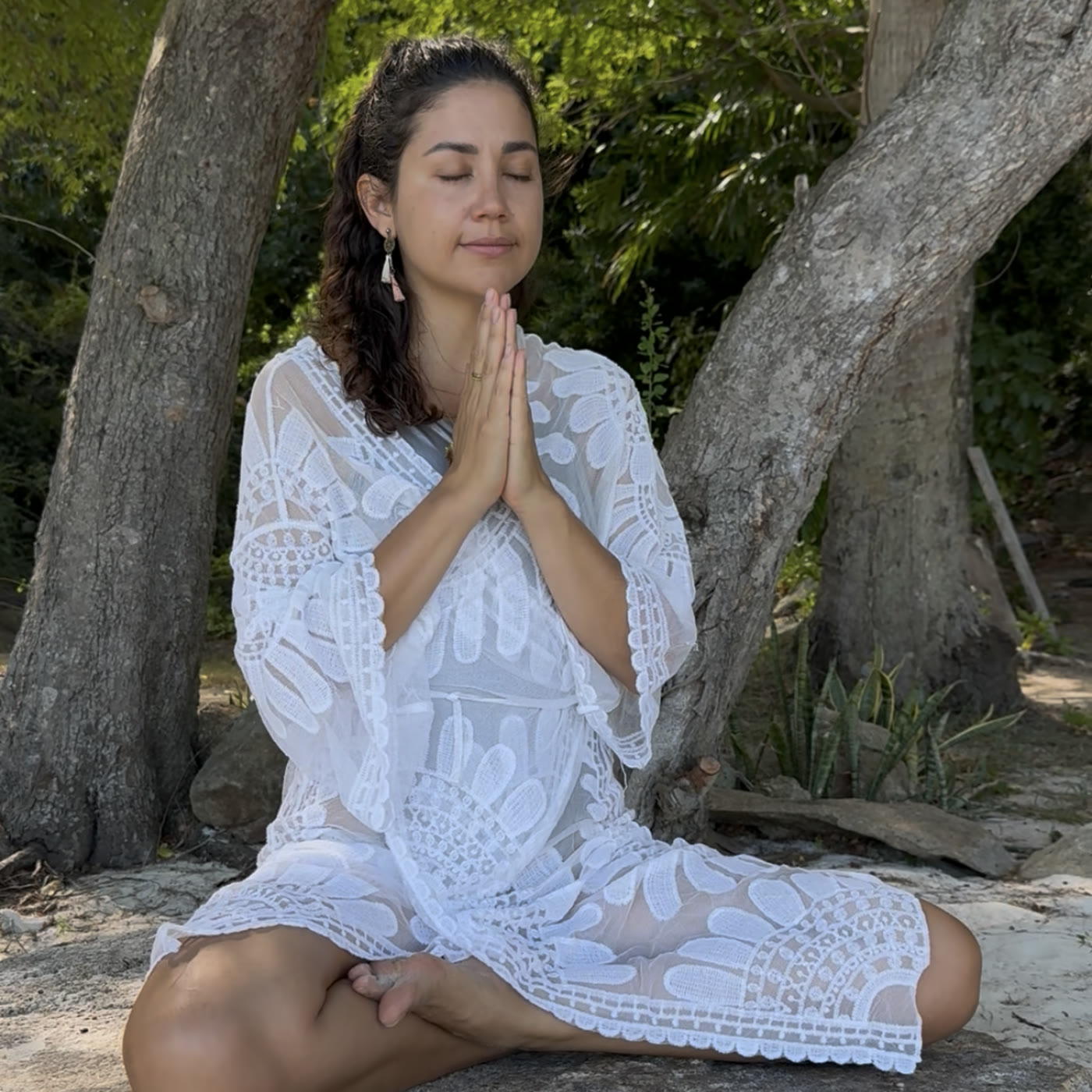 Diana meditating in prayer pose on a beach rock